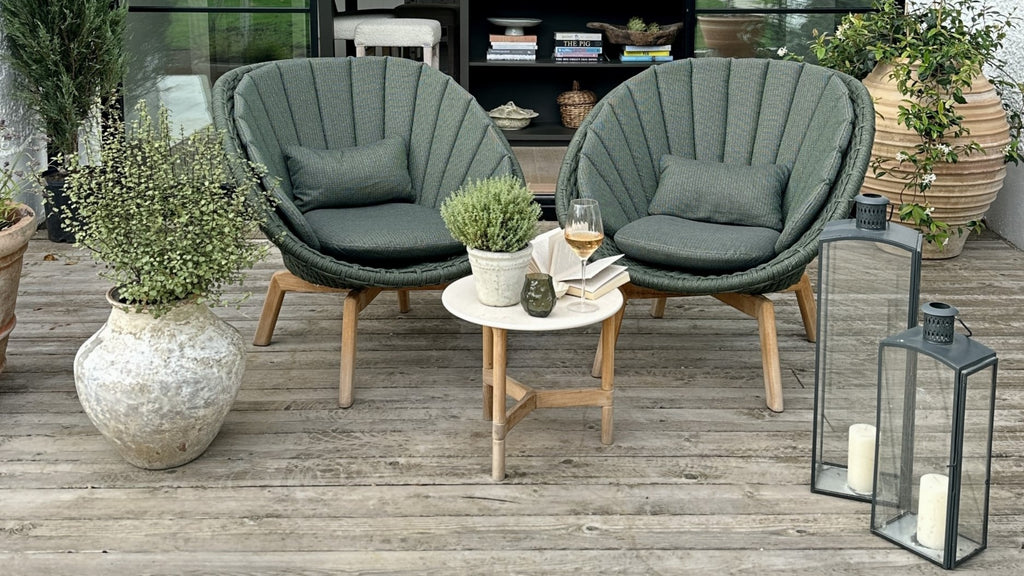 Dark green lounge chairs with teak base and white ceramic side table outdoors