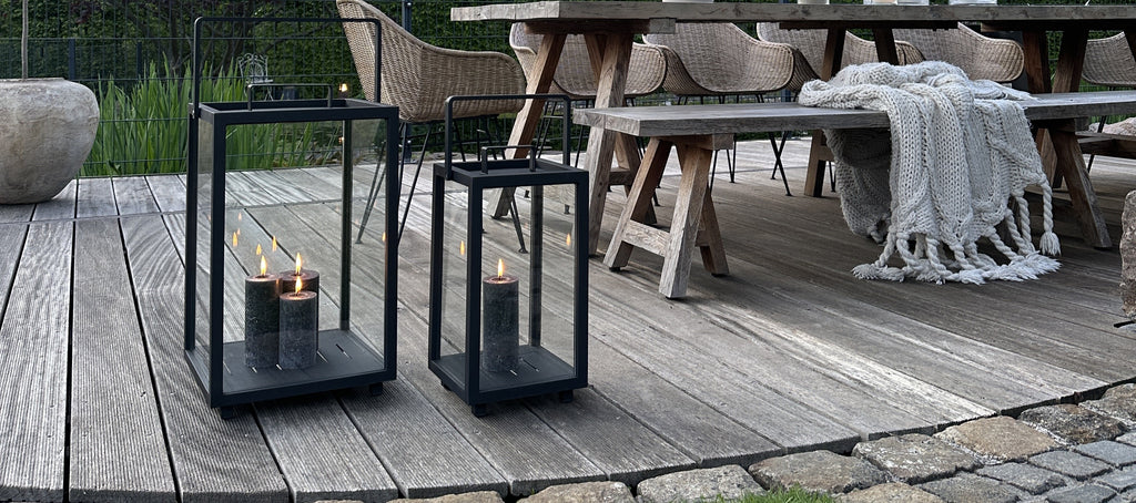 Two black lanterns with multiple grey candle lights in the garden