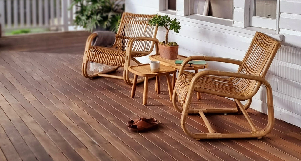Two outdoor lounge chair styled with teak side tables on a veranda