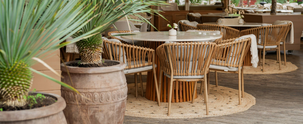 Modern restaurant interior at Swedish Josefina in Stockholm with natural Cane-line Weave Ocean chairs around a round table with palms decor