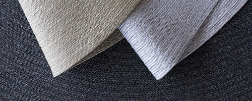 Two textured carpet samples in light colors, showcasing contrasting patterns against a darker background.