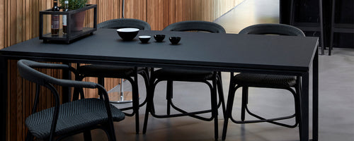 Modern black dining table accompanied by stylish chairs, featuring decorative items on the table's surface.