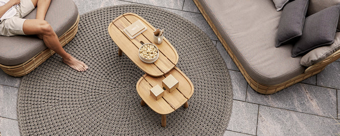 Modern lounge setting featuring a brown coffee table, grey sofa, and beige cushions.