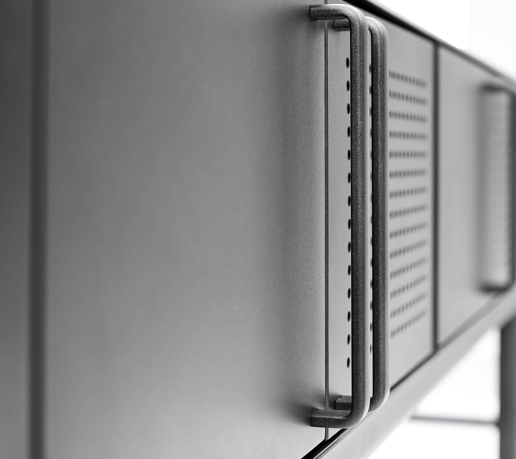 Close-up of a sleek, modern metallic surface with a handle and ventilation details, highlighting a minimalist design.
