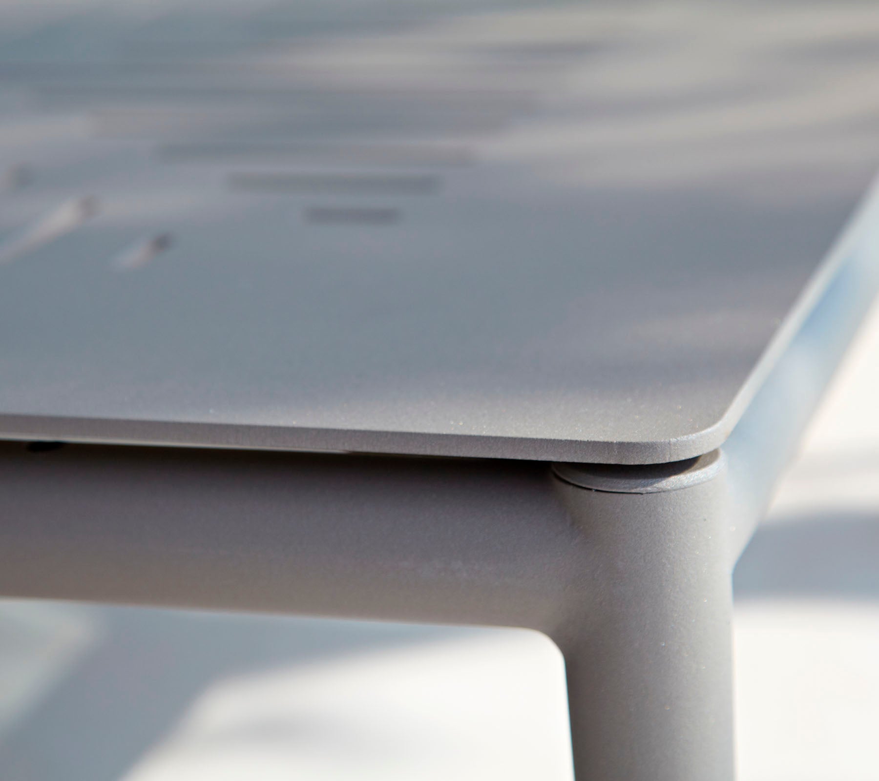 Close-up of a sleek, modern table with a smooth surface and subtle detailing. The design emphasizes clean lines and minimalistic style.