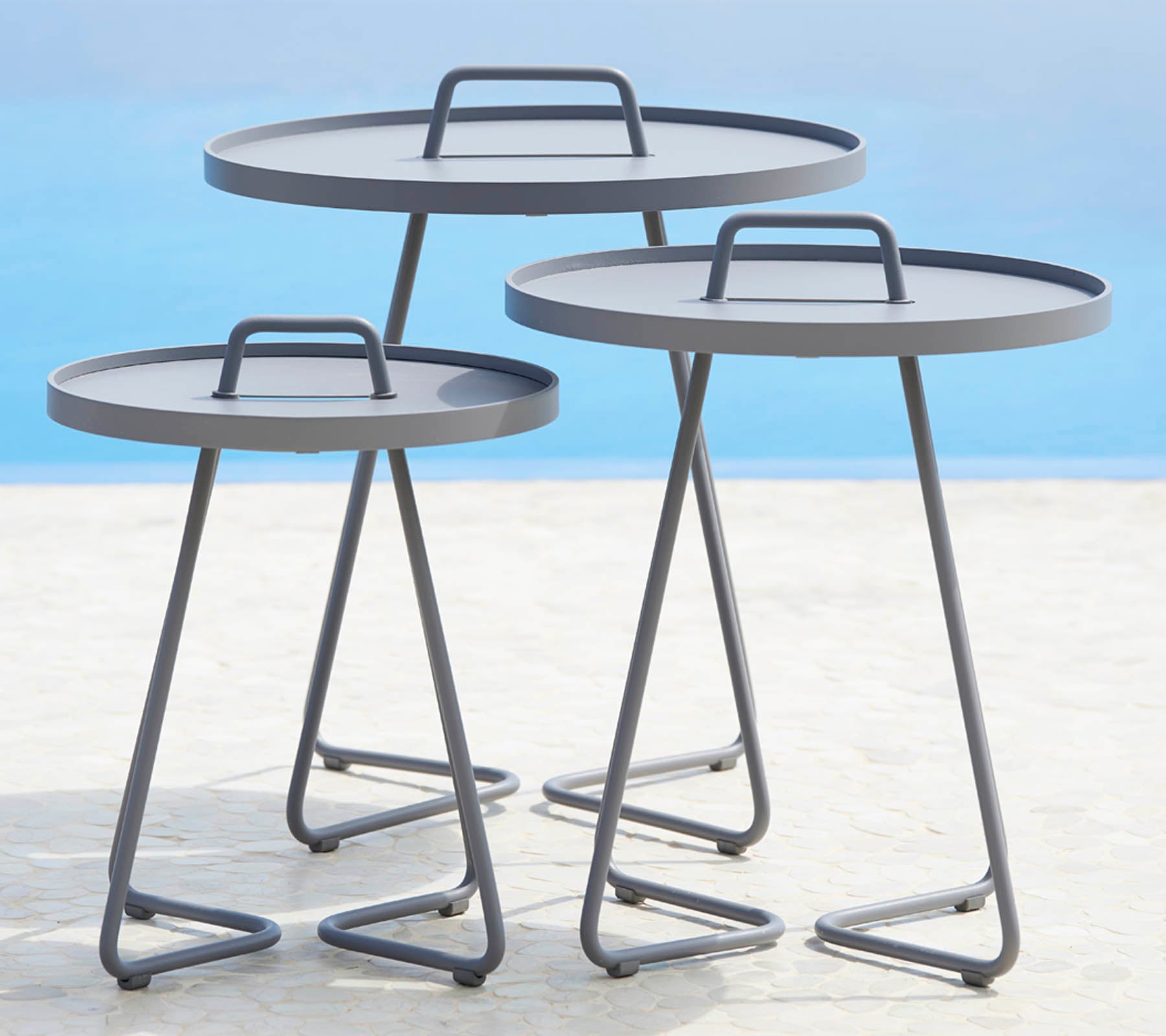 Three modern round tables with sleek metal frames and flat surfaces, arranged in varying sizes. Perfect for versatile styling options.