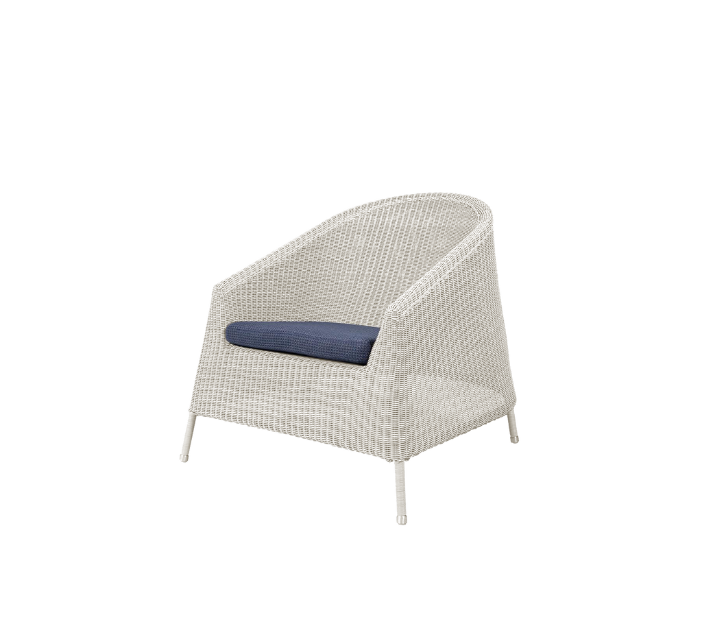 Modern white chair with a blue cushion in a lounge setting.