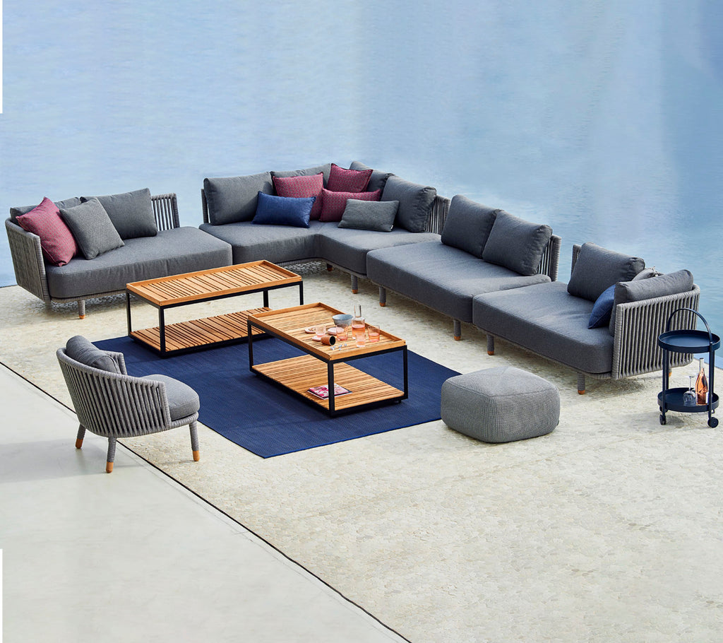 Contemporary seating arrangement featuring a modular gray sofa with colorful cushions, coffee tables, and a matching accent chair.