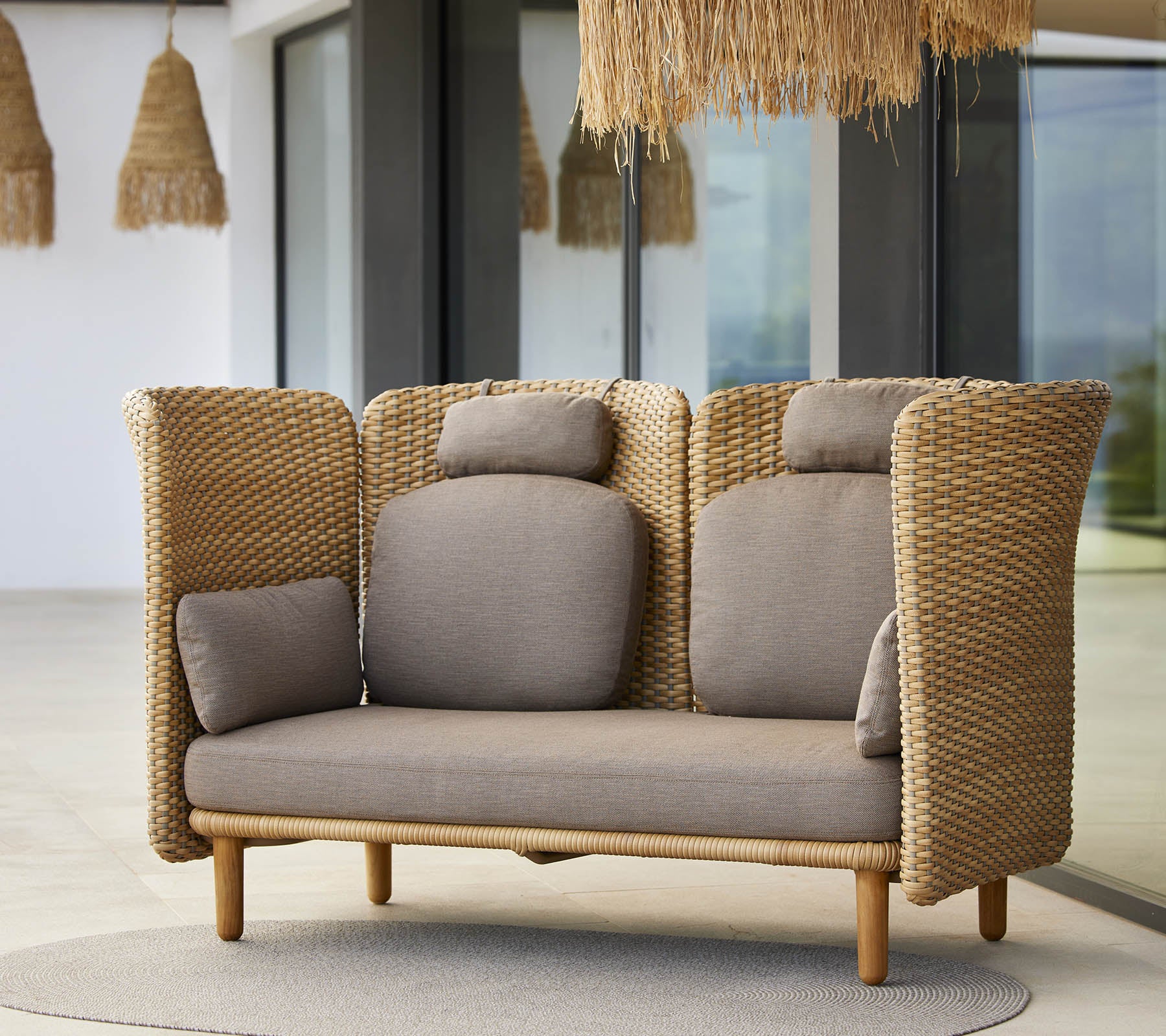 A stylish lounge sofa featuring woven sides and soft cushions, designed for comfort and relaxation. Ideal for modern spaces.