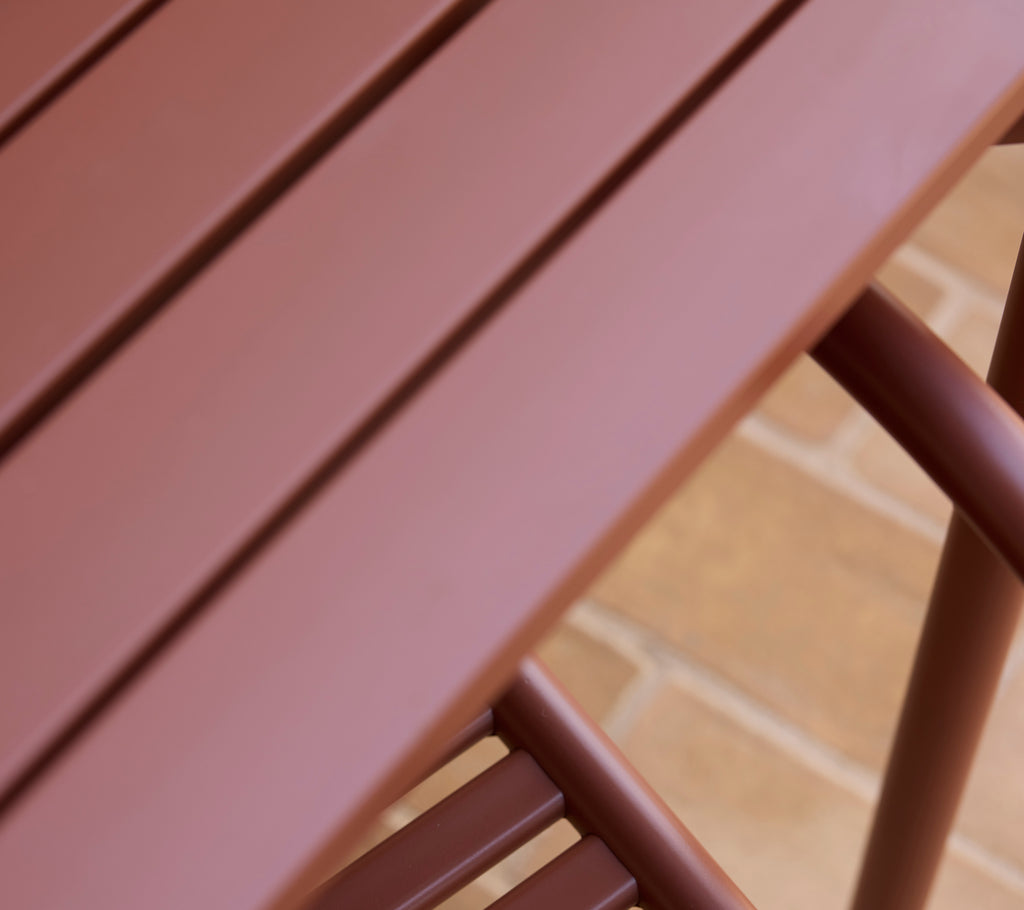 A close-up view of a desert red Bliss table showcasing its smooth surface and sleek design.