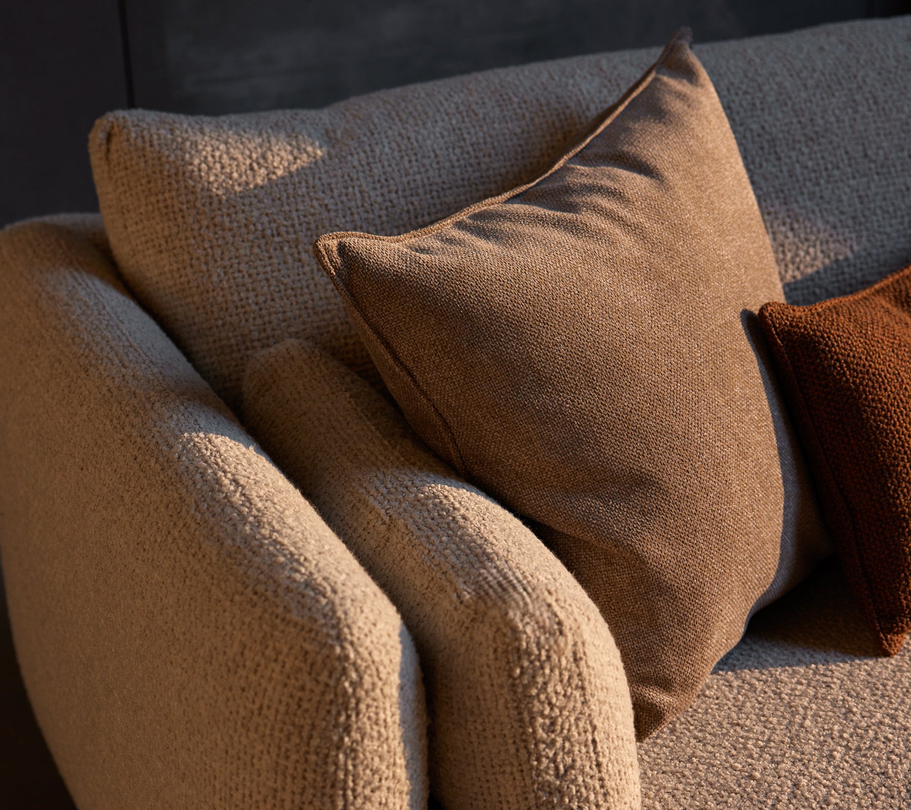 Cozy corner sofa featuring textured fabric with Essence scatter cushions in warm tones, adding comfort and style to the space.