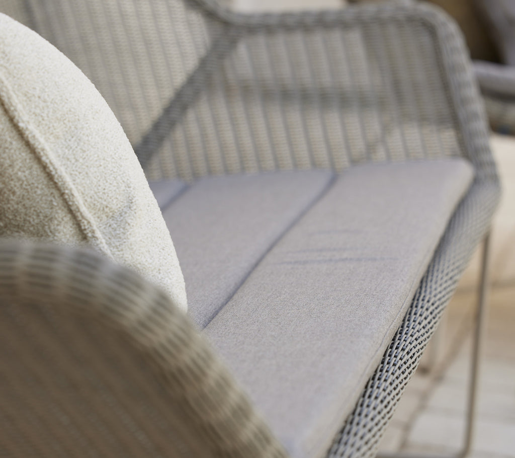 Modern grey sofa with a plush cushion in a stylish lounge setting.