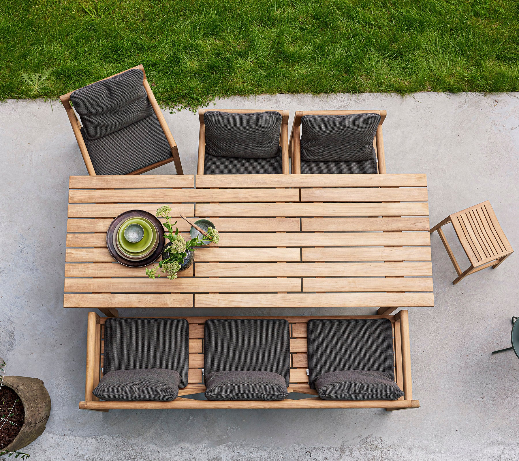 A wooden dining table with four cushioned chairs and a bowl of greenery, arranged for an inviting gathering.