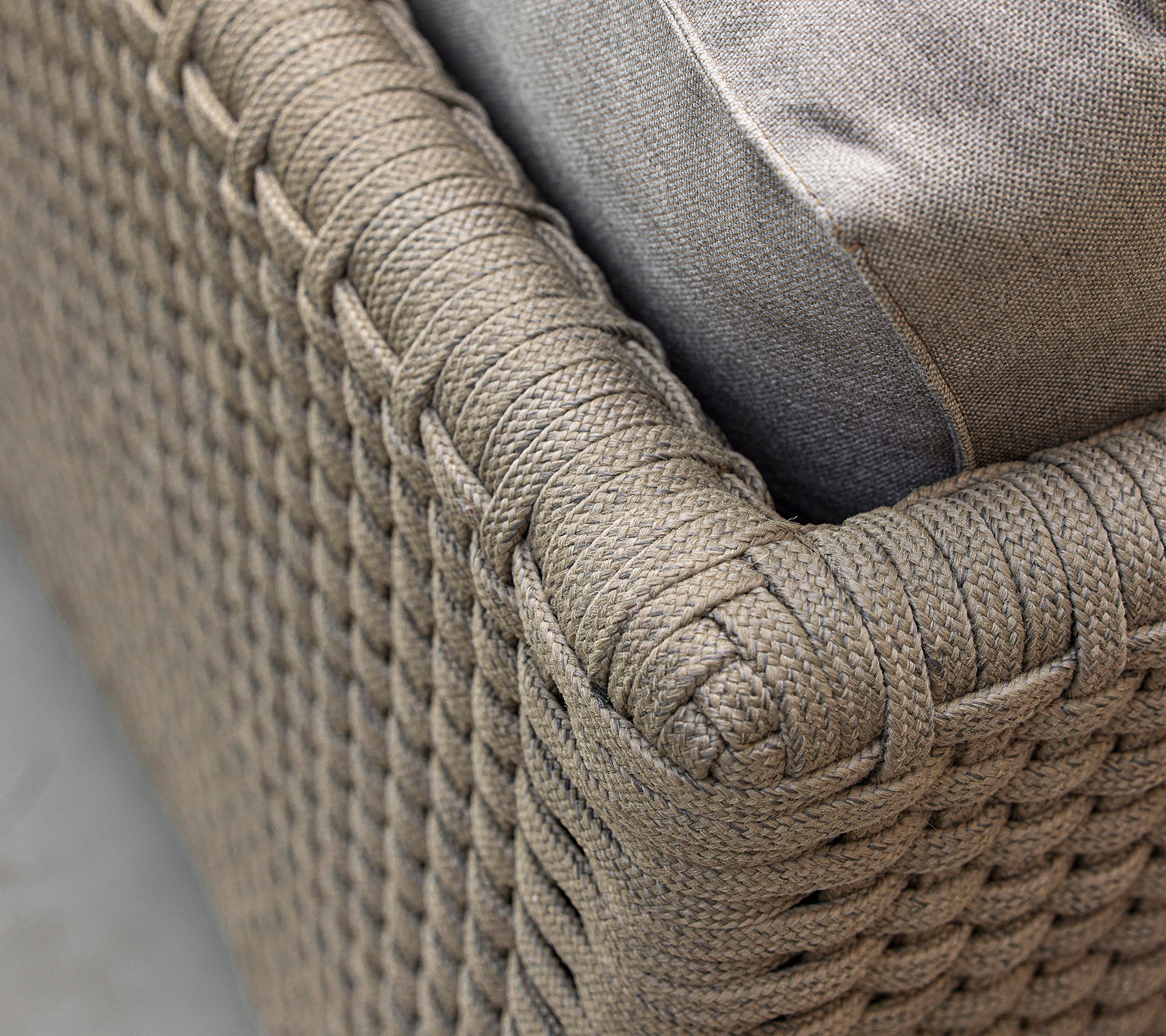 Close-up view of a woven, textured furniture piece with a soft cushion, highlighting its intricate design and neutral color scheme.