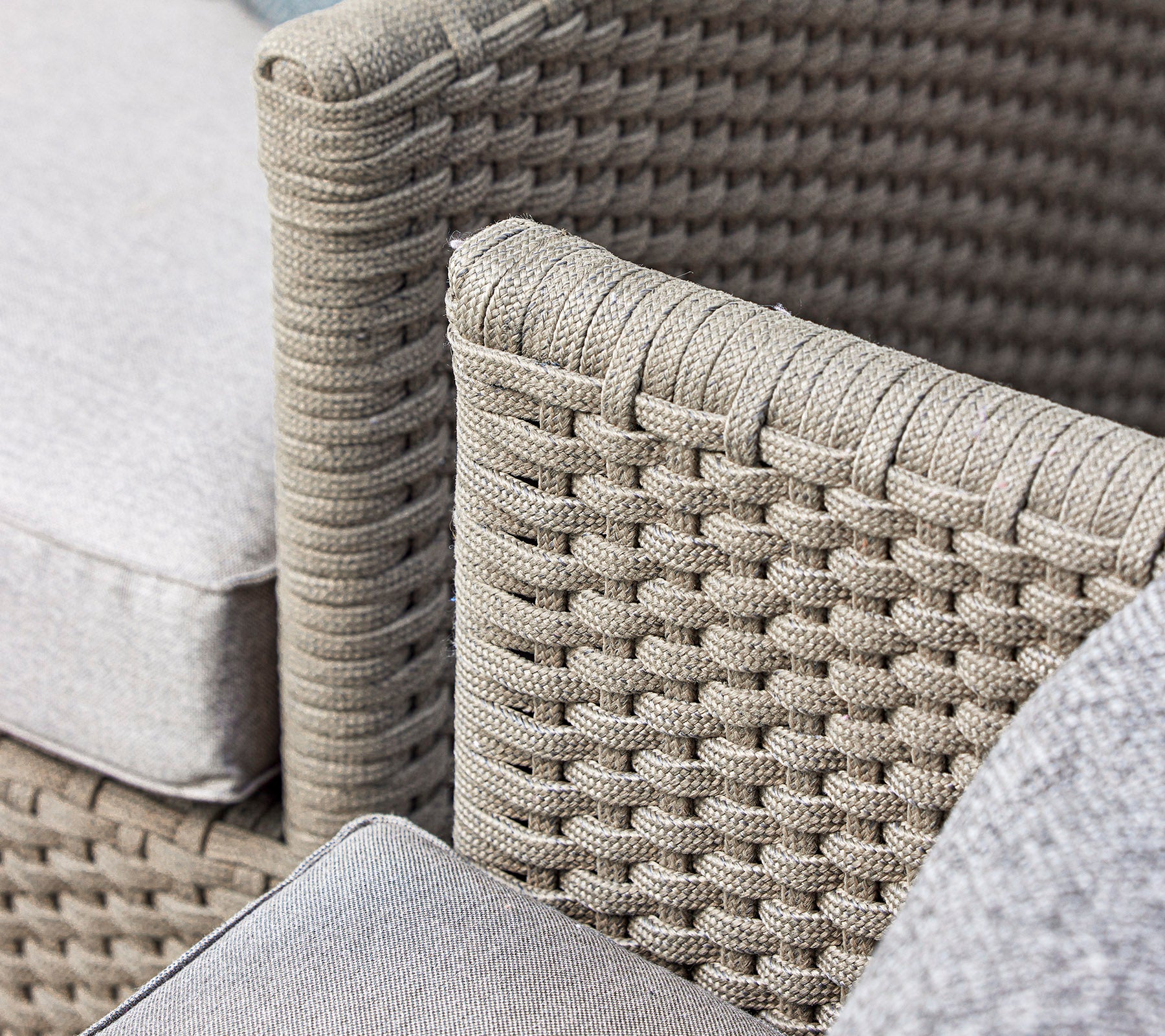 Close-up of a woven wicker chair design featuring soft cushions in a neutral tone, showcasing craftsmanship and texture.