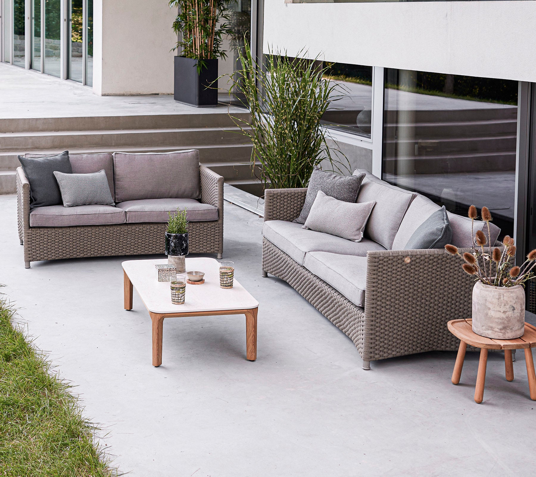 Modern outdoor seating arrangement featuring a sofa, loveseat, and a coffee table with decorative elements. Stylish and inviting atmosphere.