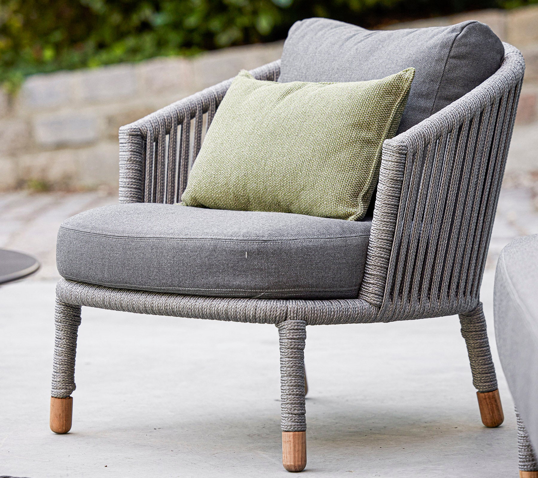 Stylish gray chair with a rounded design and cozy green cushion, featuring textured fabric and natural wood legs. Perfect for relaxation.