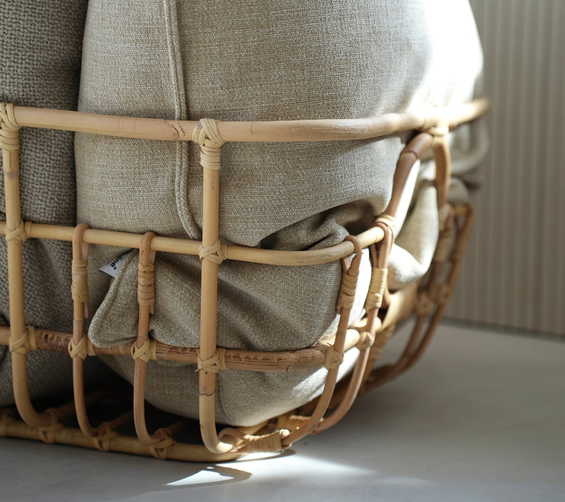 Beige cushion nestled in a woven basket, showcasing a bohemian aesthetic.