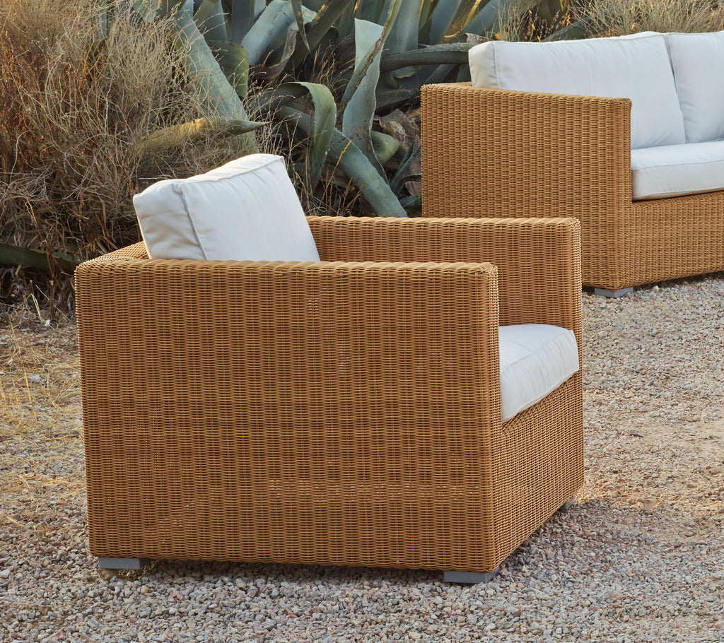 Tan armchair with white cushion in a modern lounge setting.