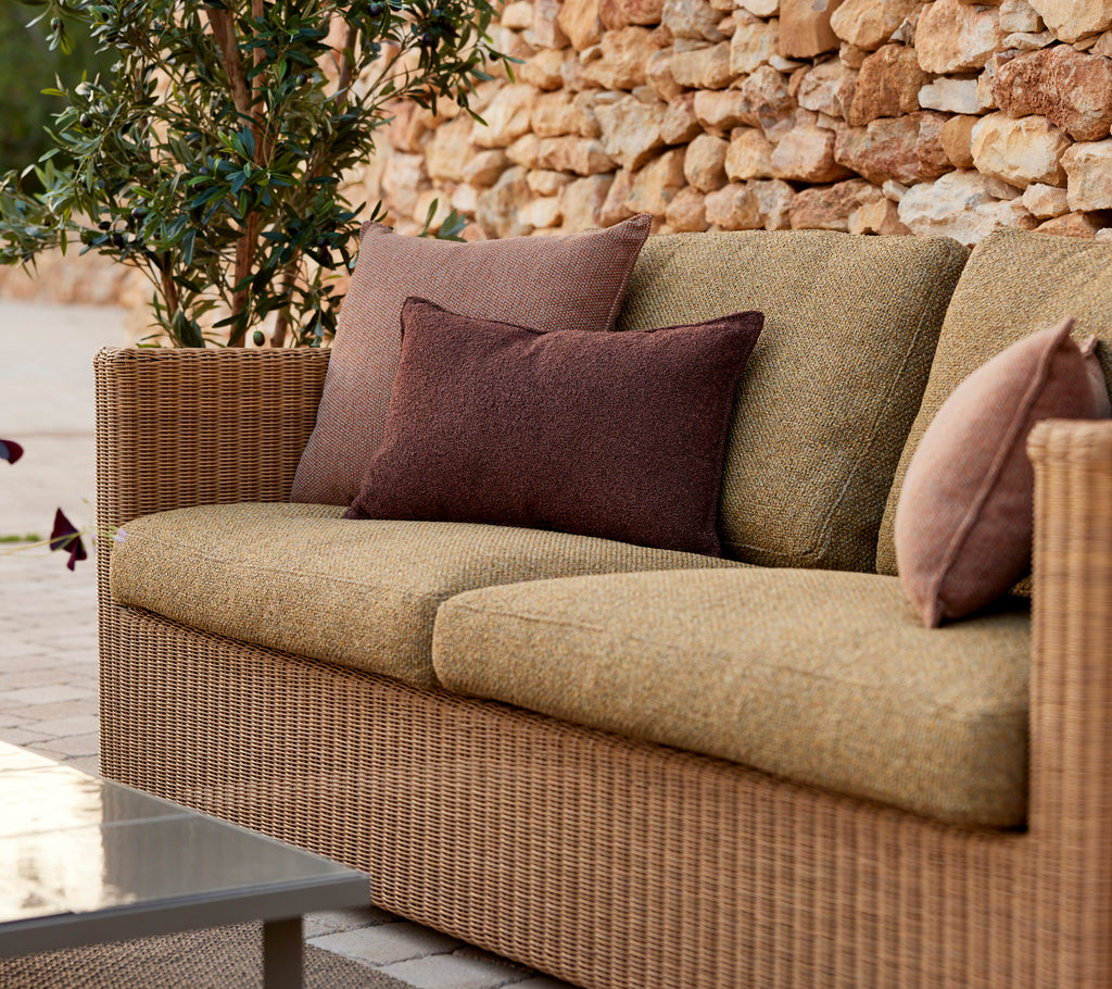 Modern beige sofa with purple and brown cushions in a lounge setting.