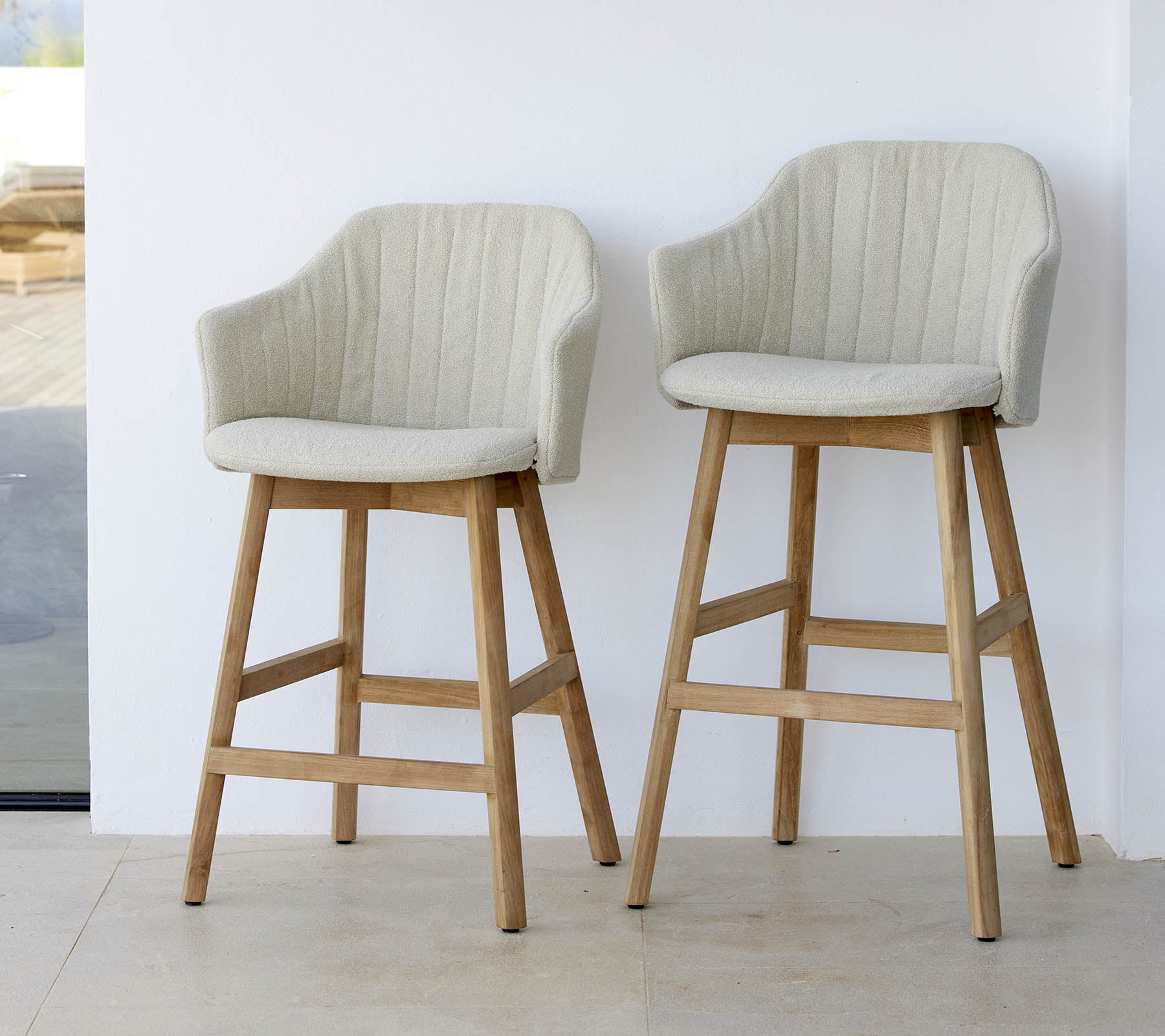 Two stylish, light-colored chairs with curved backs and wooden legs, showcasing a modern and comfortable design.