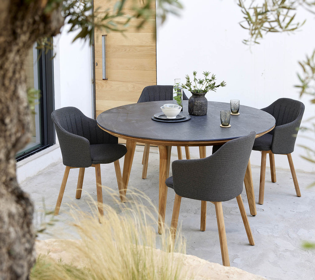 A round table surrounded by four stylish chairs, featuring a centerpiece of flowers and a simple table setting.