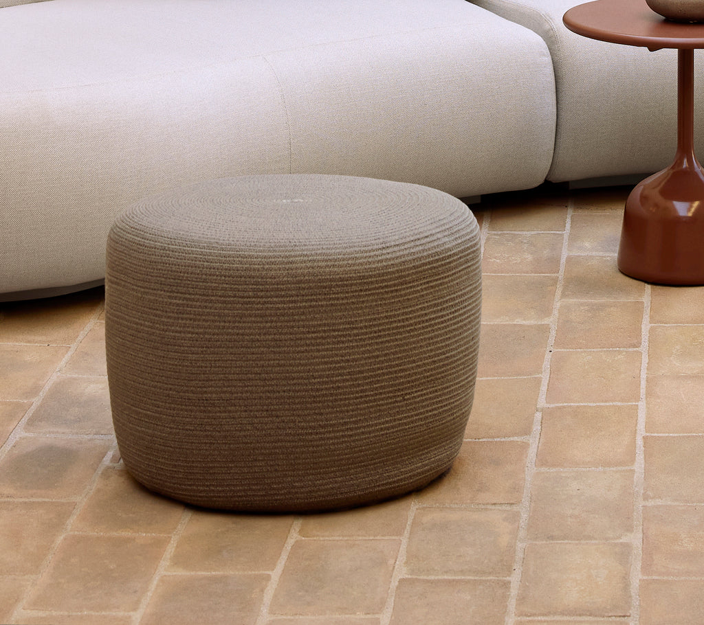 Small taupe circle footstool with a textured surface, complementing contemporary furniture and decor styles.