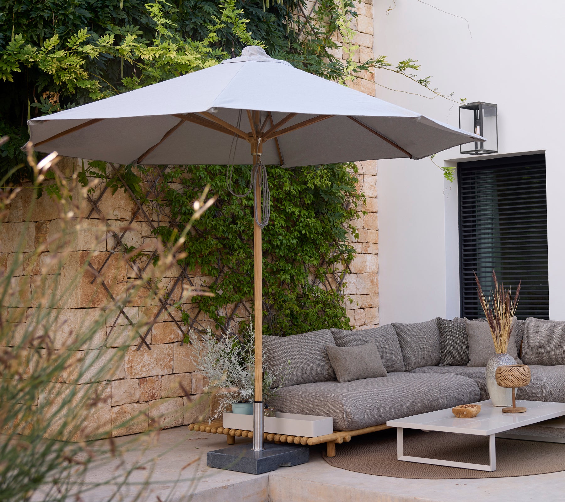 Modern lounge area with a grey sofa, white table, and grey umbrella.
