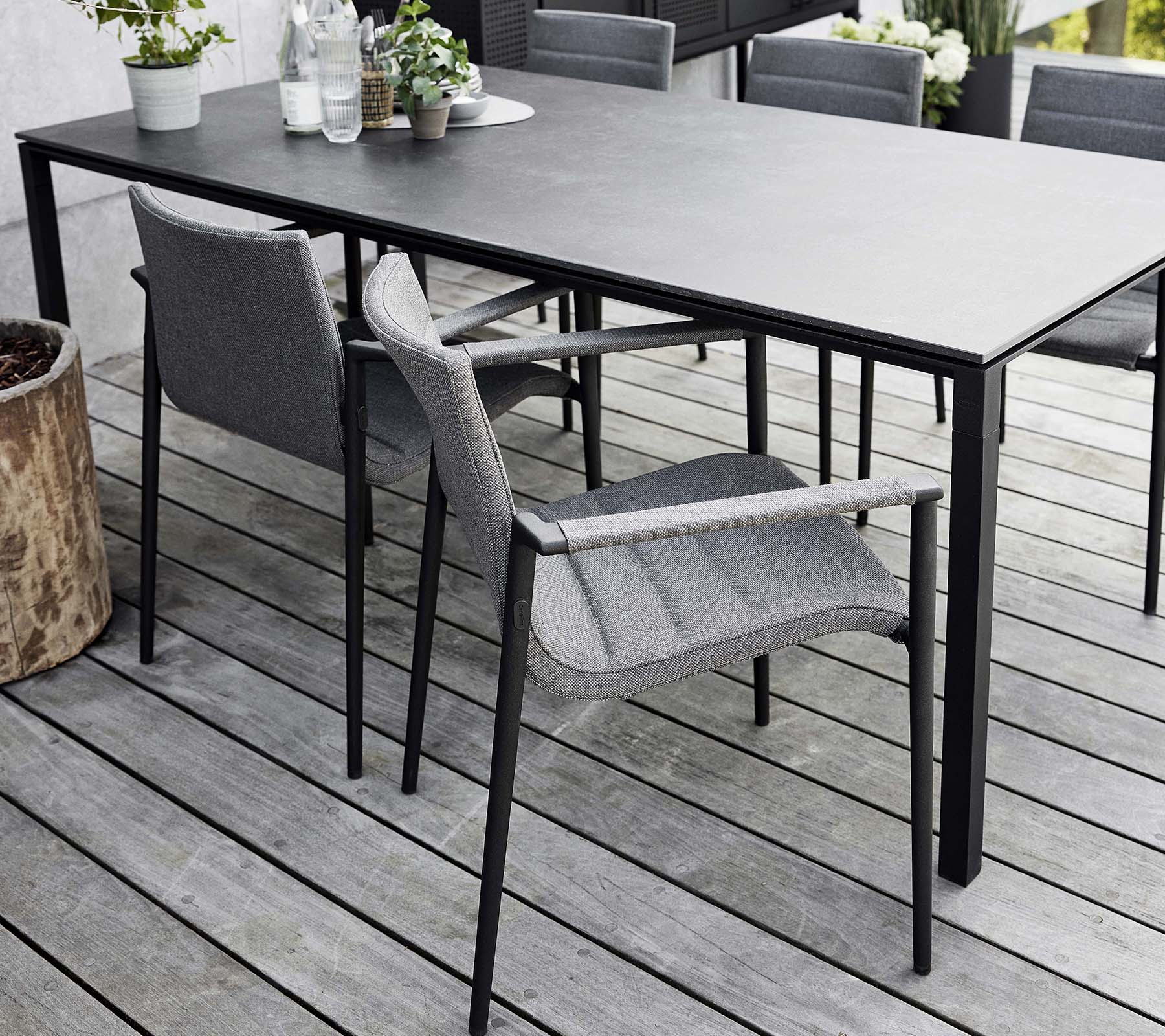 Stylish dining setup featuring a sleek table and modern gray core chairs, surrounded by natural elements and greenery.