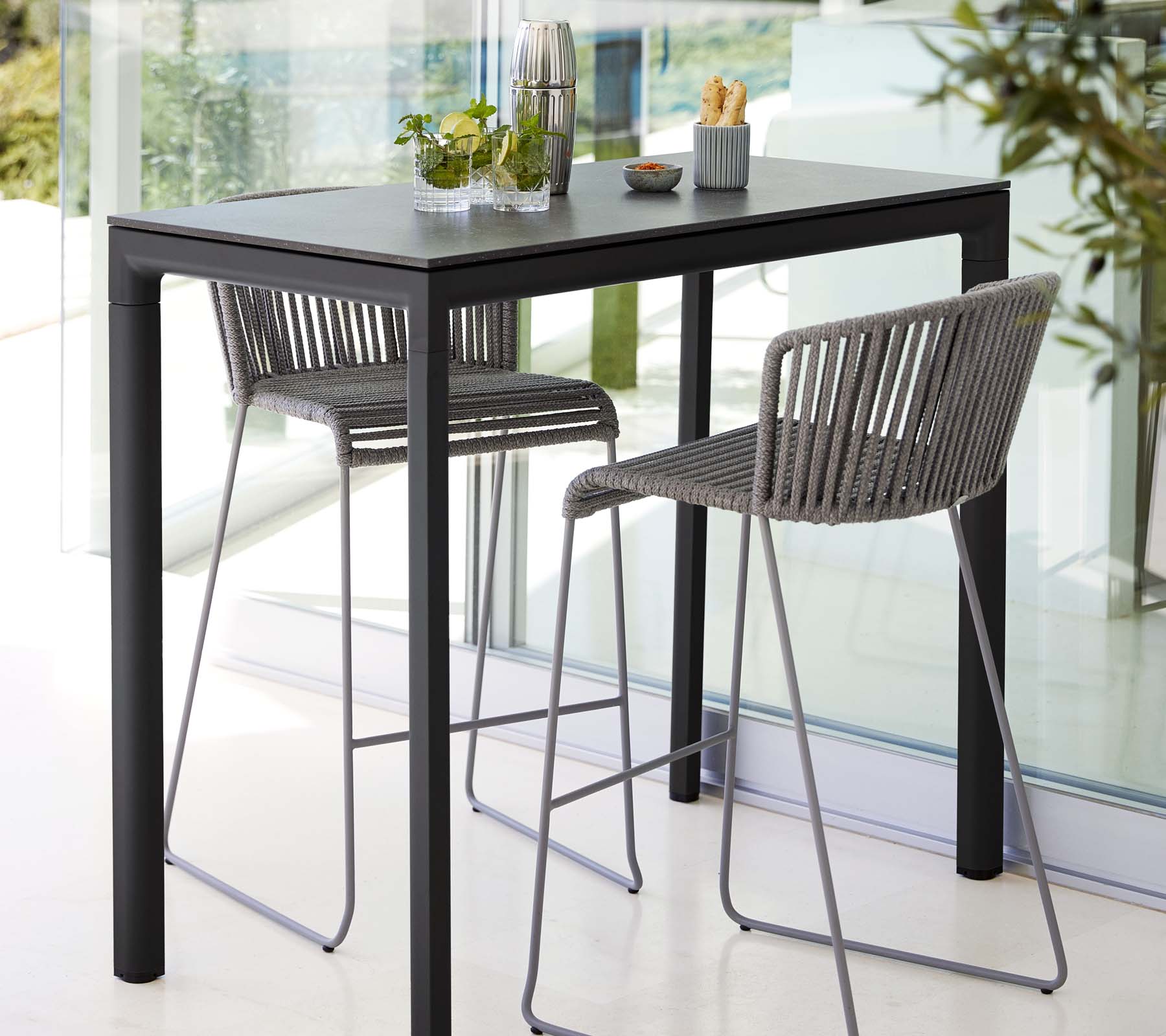 Modern table with two stylish stools, featuring a sleek design, paired with decorative plants and minimalistic dining accessories.
