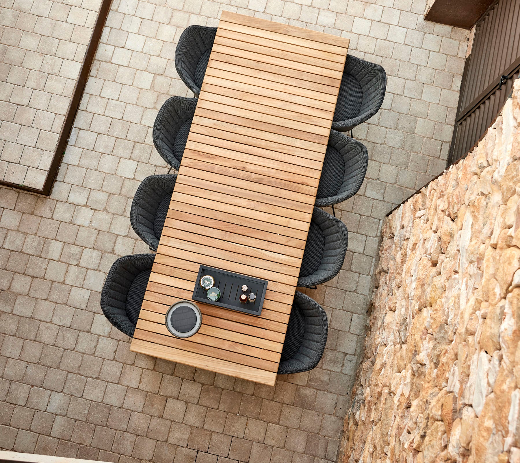 A long wooden table with a sleek design, surrounded by four modern chairs, featuring a decorative centerpiece.