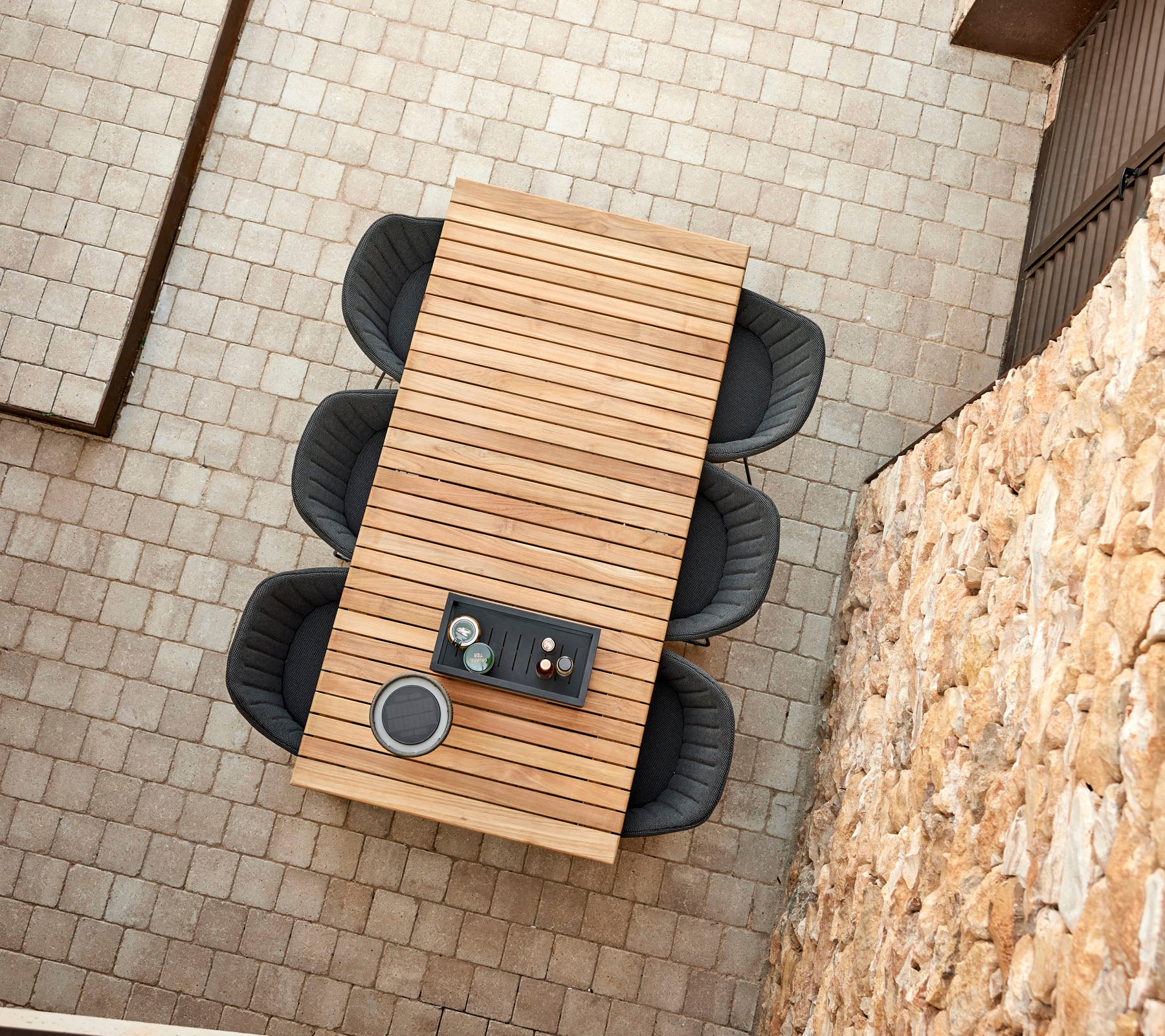 A modern wooden table with four stylish black chairs, featuring a central arrangement with beverages and snacks.