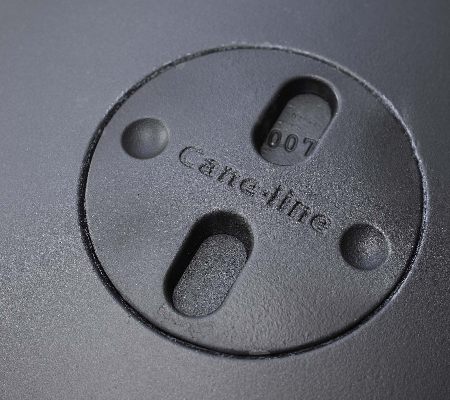 Close-up of a circular feature with engraved "Cane-line" logo and two slots, part of a fire pit design.