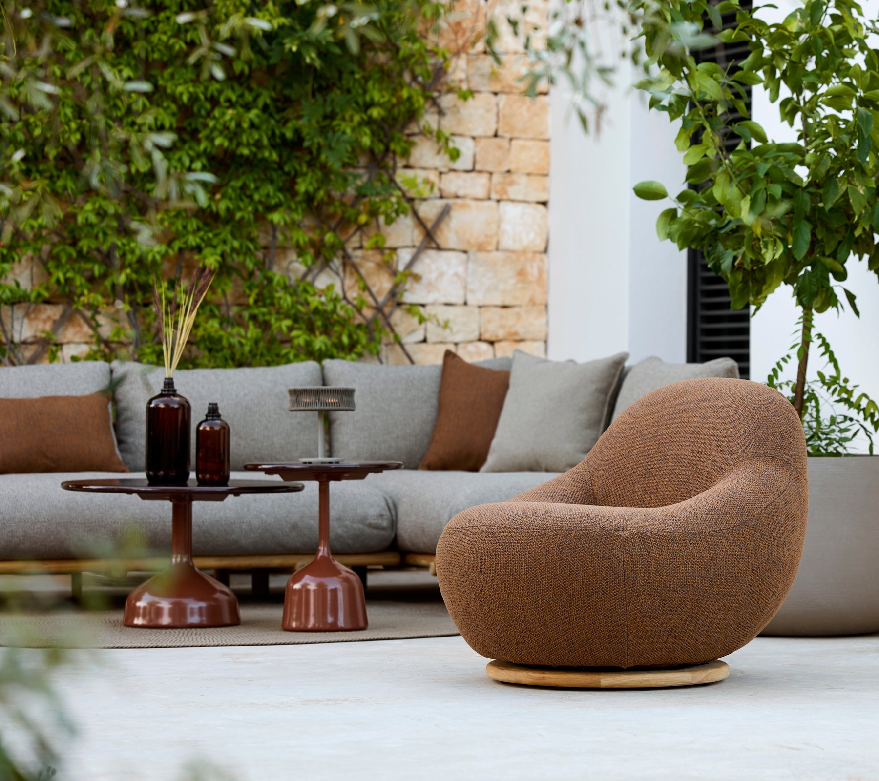 Modern lounge area with a brown armchair, grey sofa, and brown side table.