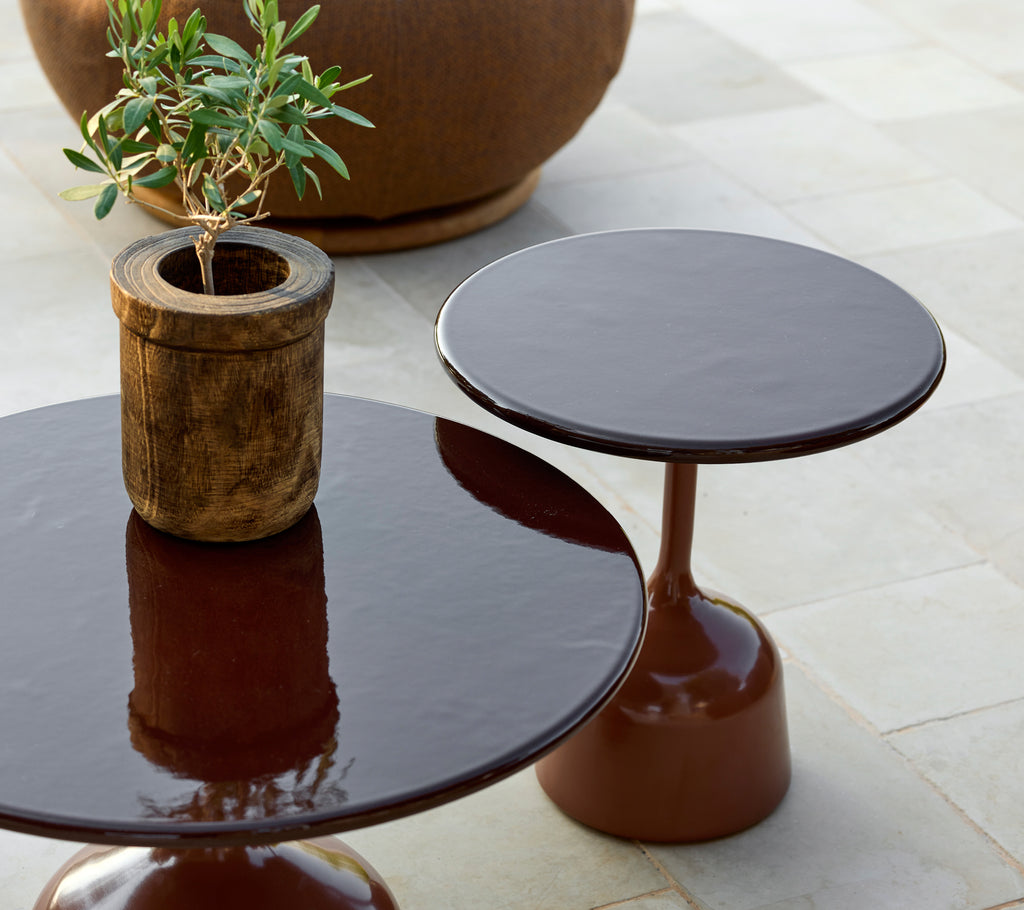 Two modern brown tables with a potted plant in a stylish lounge setting.