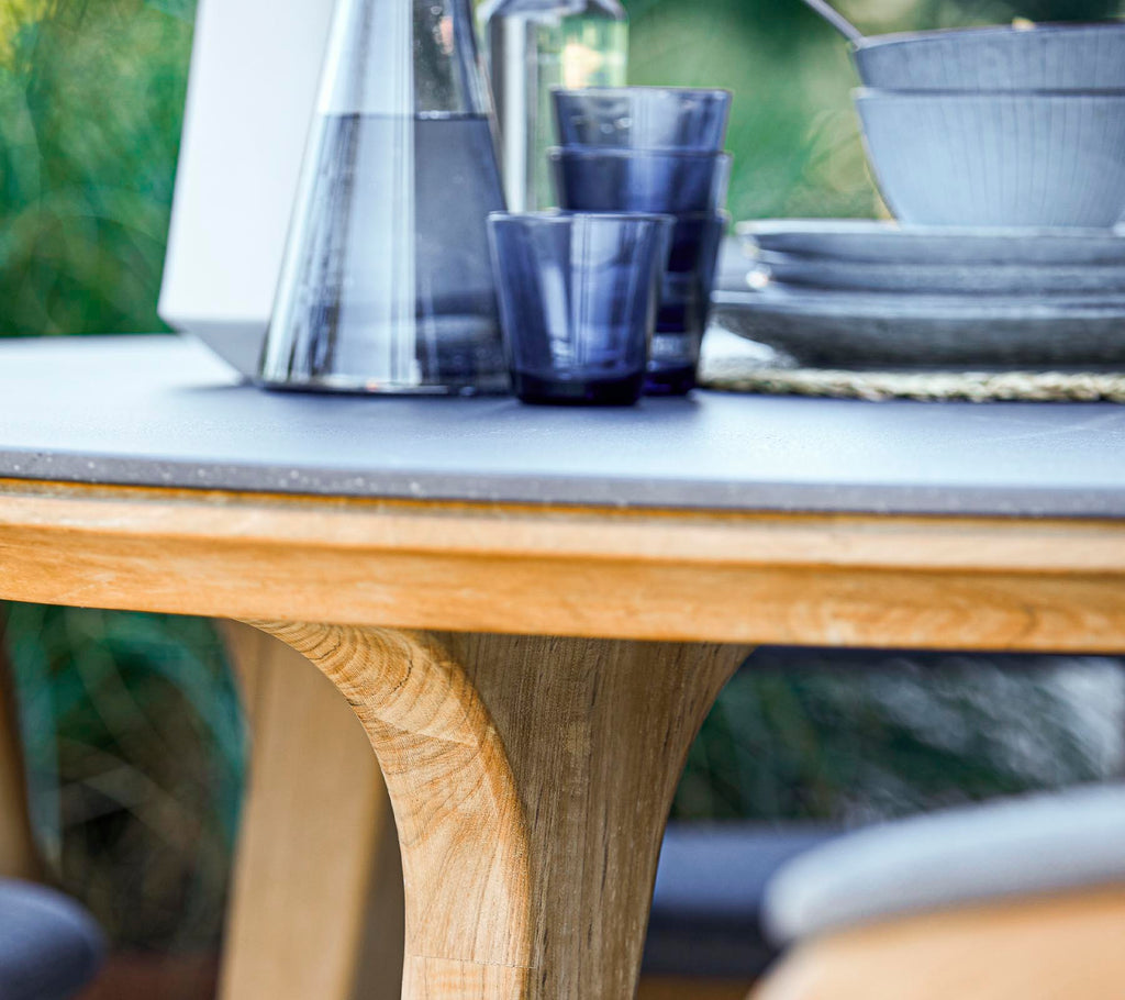 A round wooden table featuring a smooth surface, accompanied by glassware and ceramic dishes, creating a stylish dining setup.