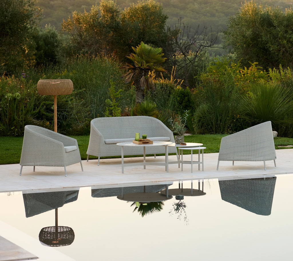 Modern grey sofa and chair with white table in an outdoor lounge setting.