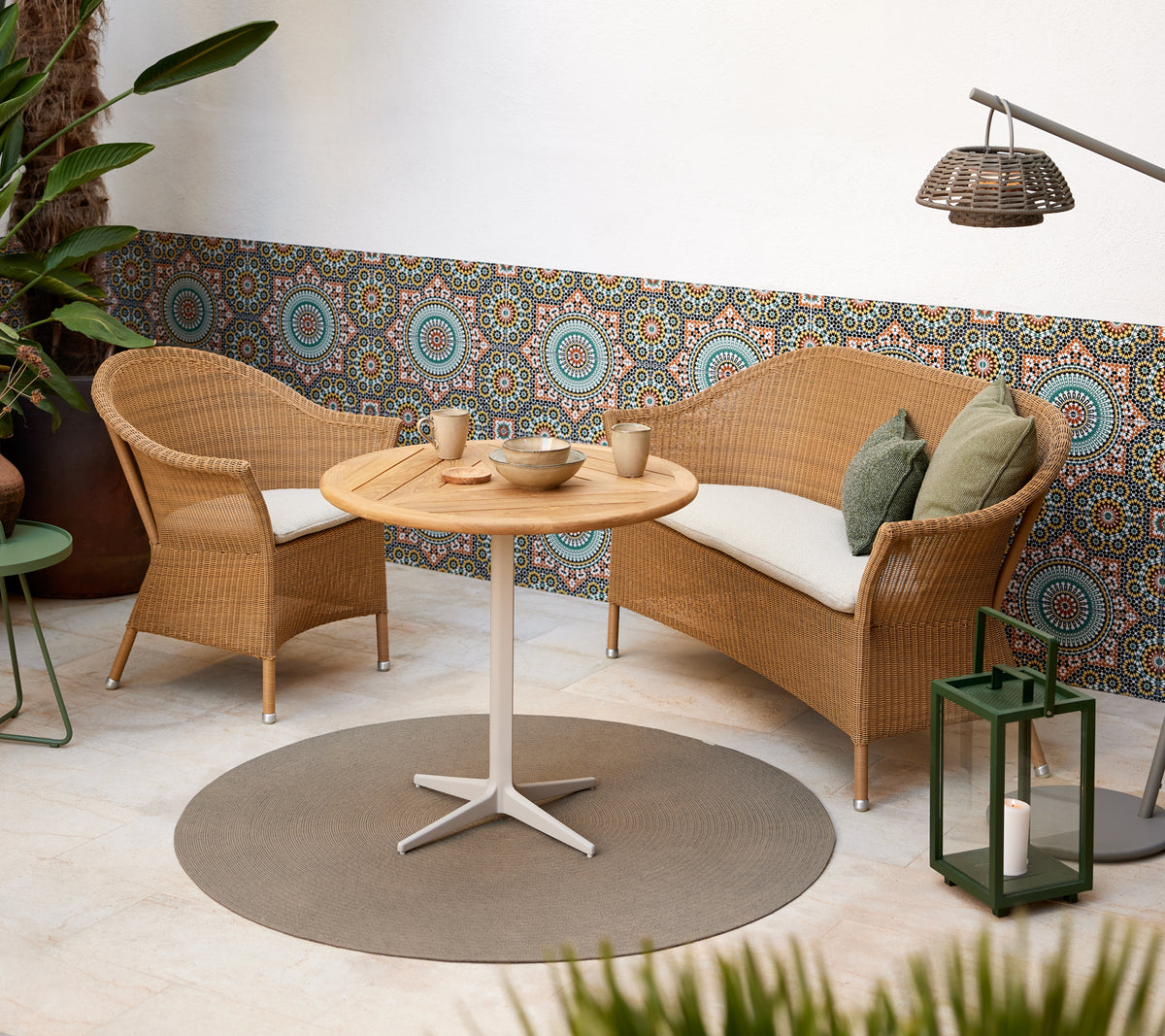 A cozy seating area featuring woven chairs and a round table, complemented by vibrant circular patterns in the background.