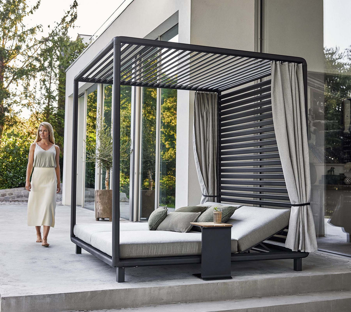 A stylish cabana with a modern design, featuring a comfortable lounging area and soft curtains, set in a serene environment.