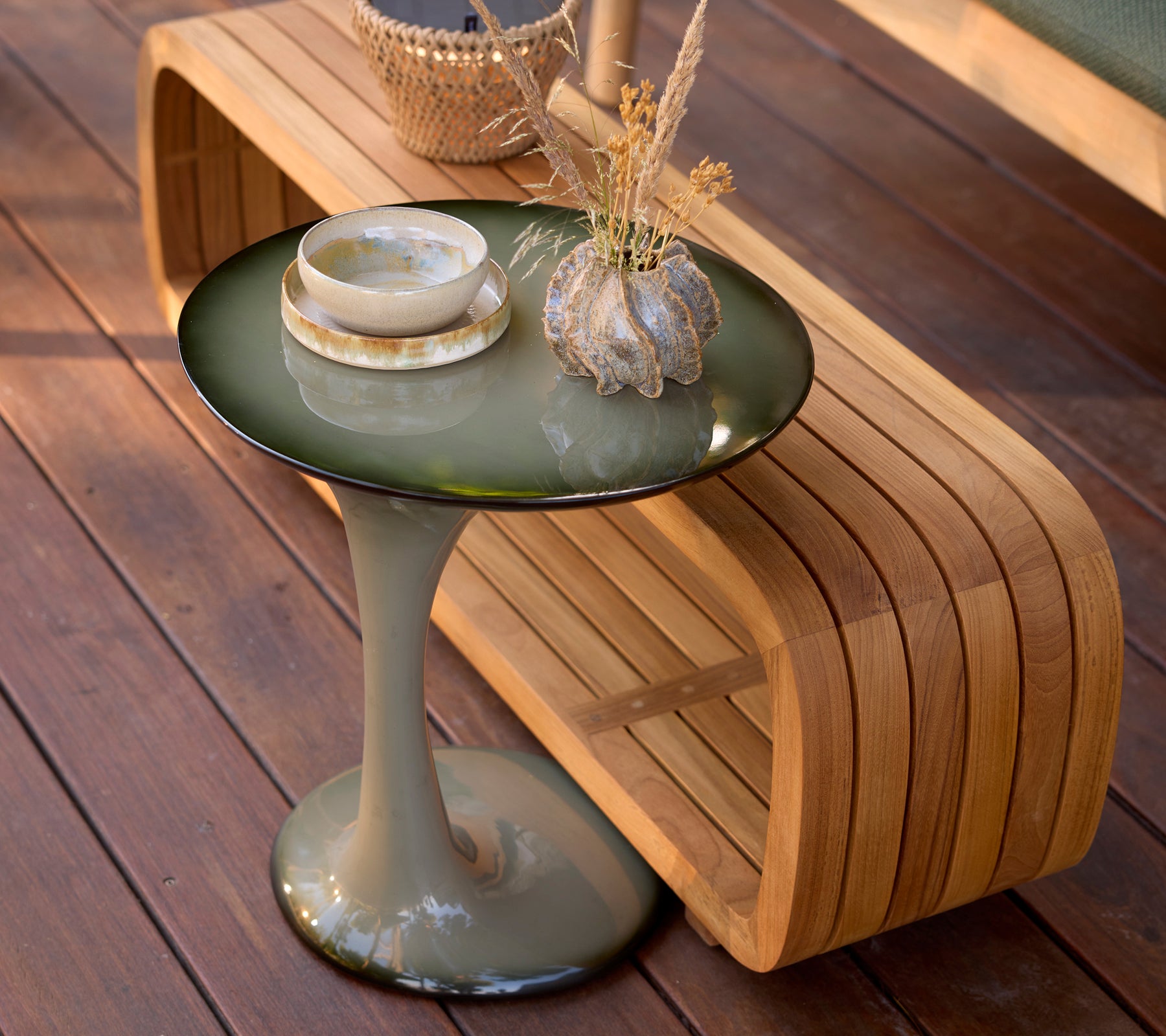 Green side table and a wooden bench in a modern lounge setting.