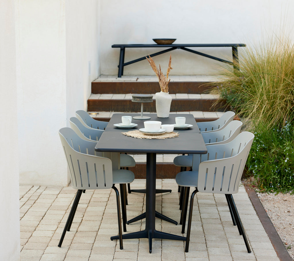 A stylish table set with six lava grey chairs, featuring a complementary aluminum bench and decorative elements like vases and dishes.