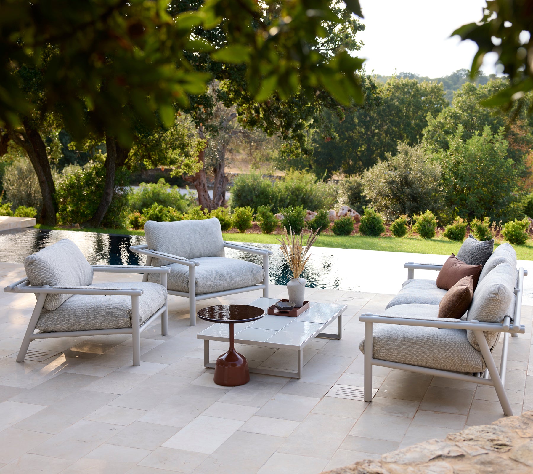 Modern outdoor lounge area with white chairs, grey cushions, and a white table.