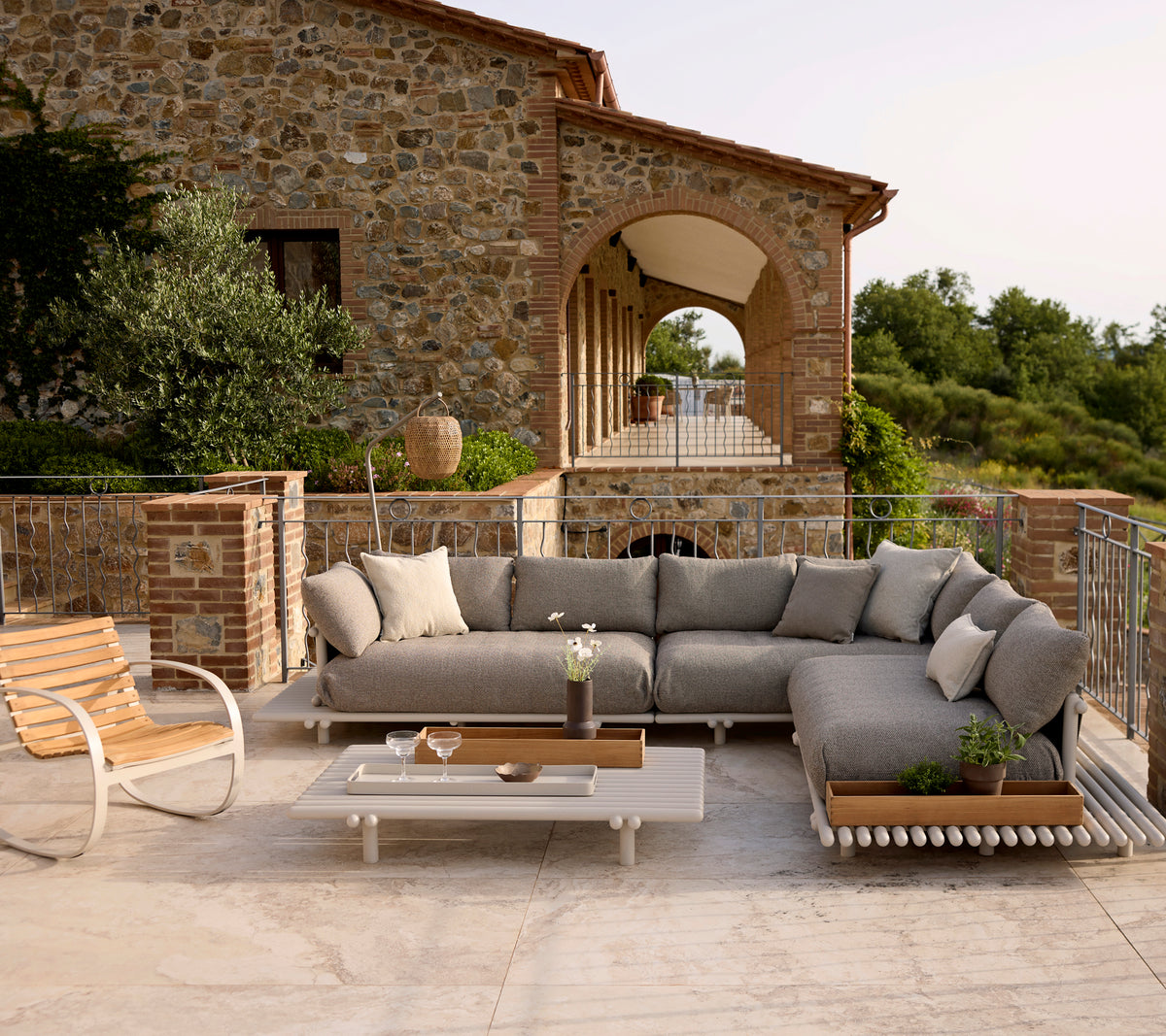 Lounge seating with plush cushions, complemented by a stylish rocking chair and a coffee table, set against a scenic backdrop.