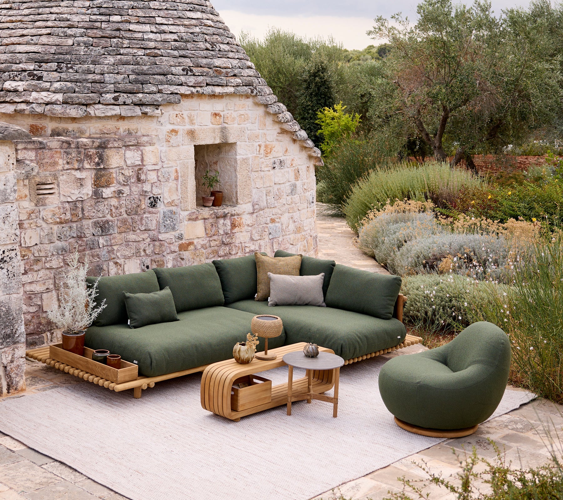 Modern green sofa and chair with a brown table in a garden setting.