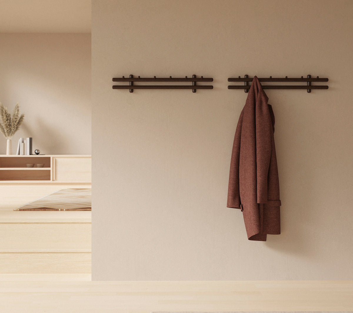 A minimalistic wall display with wooden sticks holding a coat and a gathering of rags, enhancing the rustic decor aesthetic.